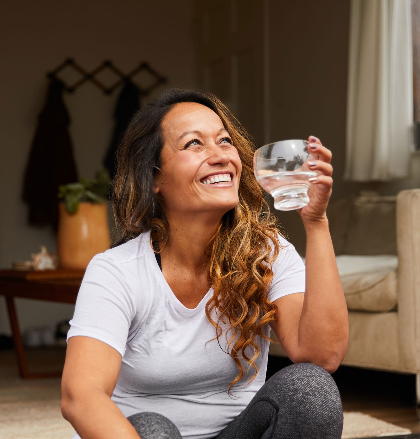 Photograph of a woman smiling while drinking from a glass of water