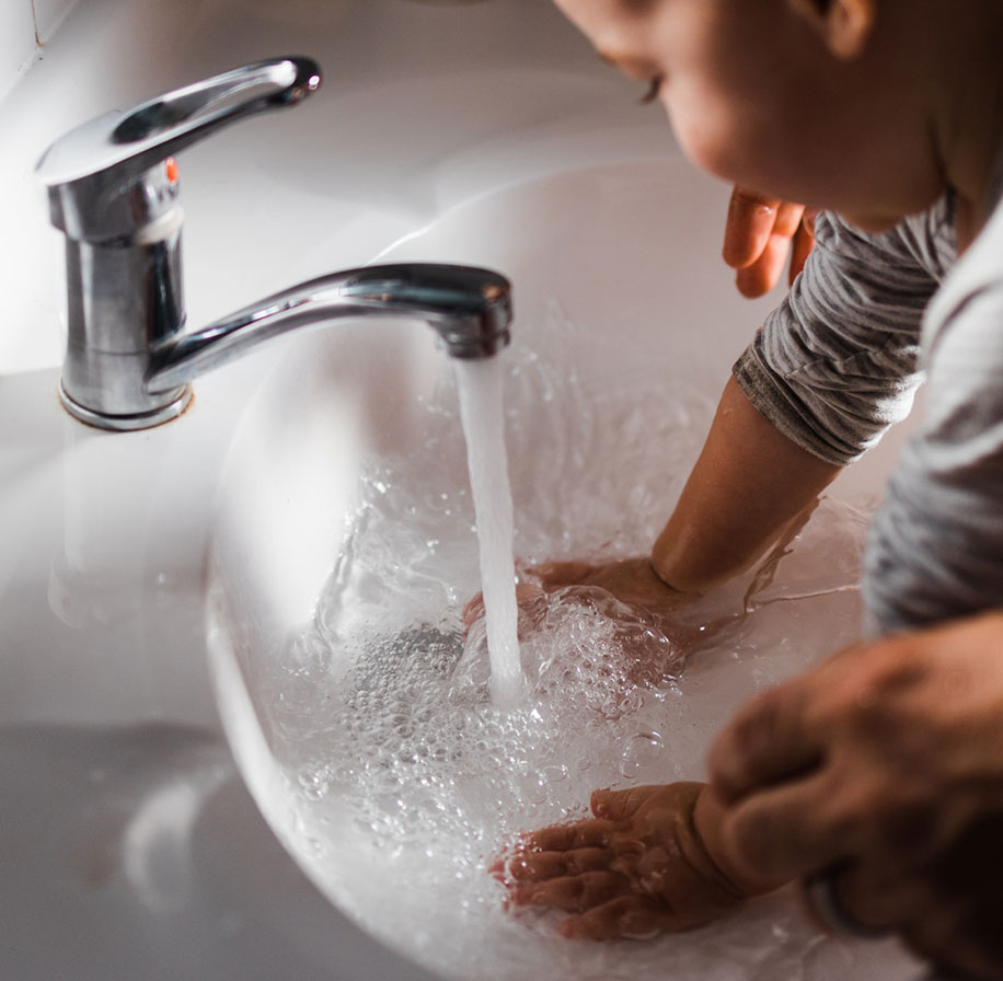 Photograph of a young child playing with water in a sink