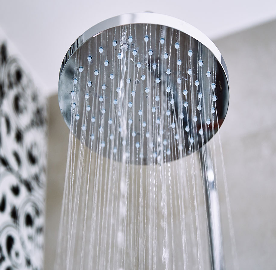 Close-up of a chrome showerhead with water flowing