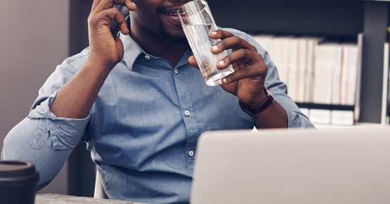 Photograph of a man talking on the phone while drinking from a glass of water